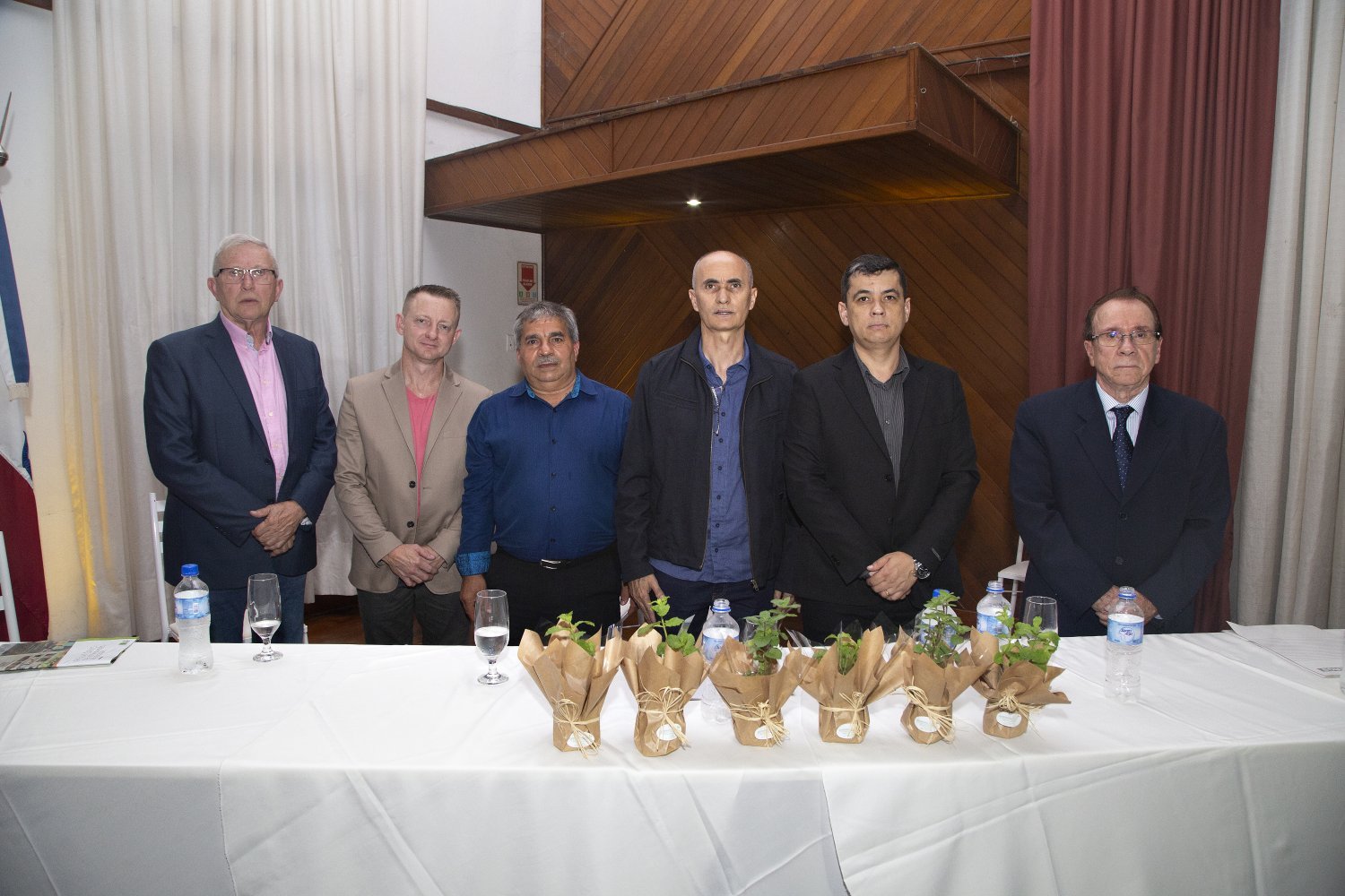 Lideranças empresariais em pé atrás de uma mesa na posse do Sindicato